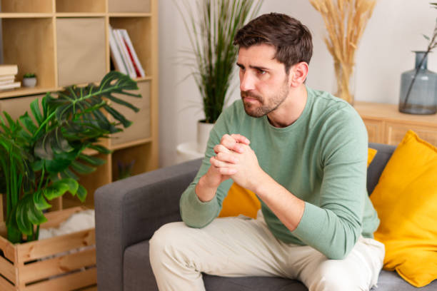 istock Pensive man sitting on couch at home 2150034858