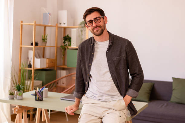 istock Confident young man sitting on desk in modern home office 2150036330