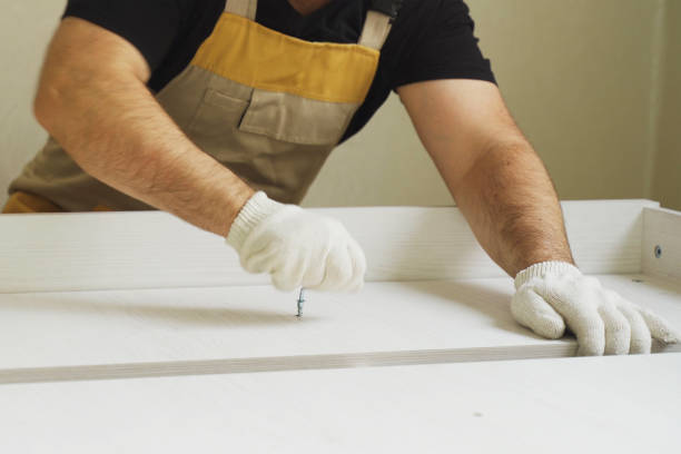 Furniture assembly. A worker fastens the parts of a bed using confirmat.