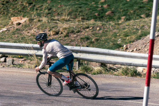 istock A man riding a bicycle on a road descending at high speed. There is a red and white pole 2150043898
