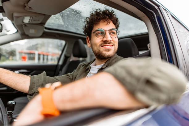Young smiling man looking away while driving his car.