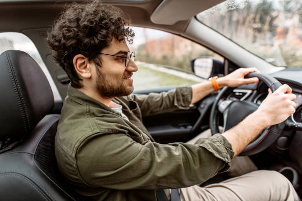 istock Young smiling man looking away while driving his car. 2150046110