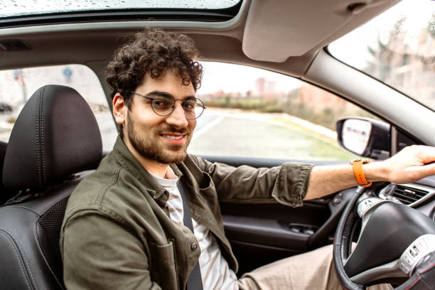 istock Young smiling man looking in camera while sitting in his car. 2150046120