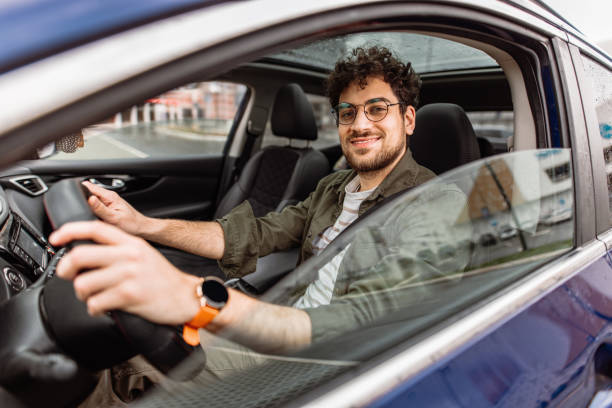 istock Young smiling man looking in camera while sitting in his car. 2150046129