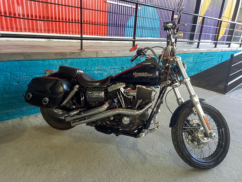 Avellaneda, Argentina - Mar 19, 2022: Shot of a black Harley Davidson motorcycle on a colorful industrial background.