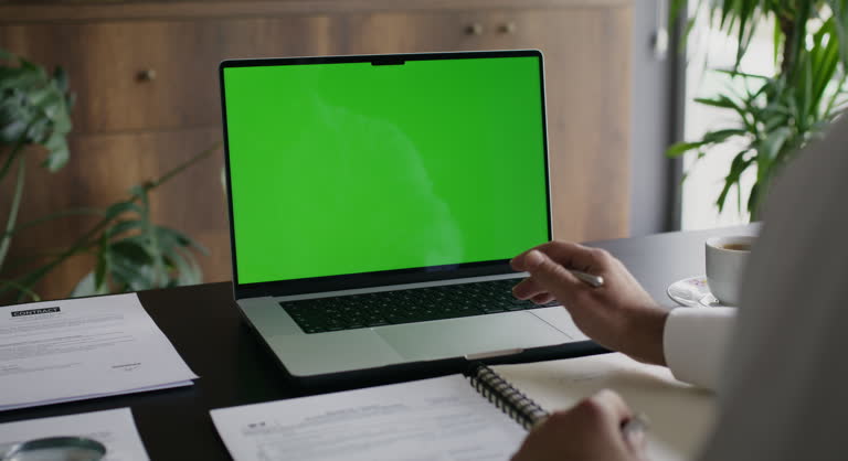 Businessman Using Laptop Computer With A Chroma Key Green Screen In The Office