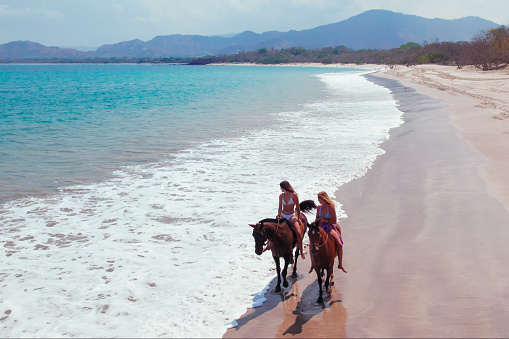 Two Women Riding Horses on the beach