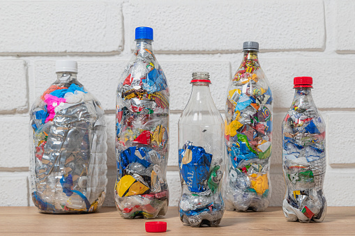 A group of five bottles of PET stuffed with plastic waste to upcycle and use as eco bricks, one of them is half filled