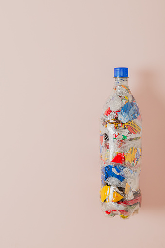 eco brick PET bottle stuffed with plastic waste on light pick background and empty space for text