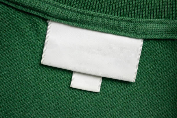istock Blank white laundry care clothes label on green shirt fabric texture background 2150050923