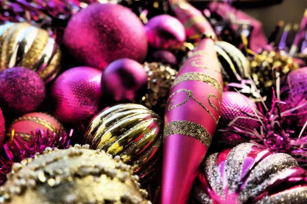 New Year's Christmas balls, tinsel and decorations close up. Decorations of golden, pink, lilac, purple, violet. Striped Christmas balls. Festive beautiful colorful background. Home holidays design