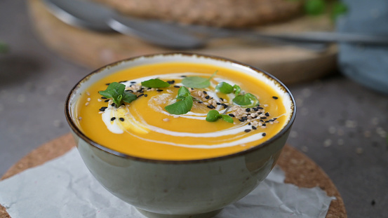 Delicious homemade creamy pumpkin soup with cream with sesame seeds and watercress.