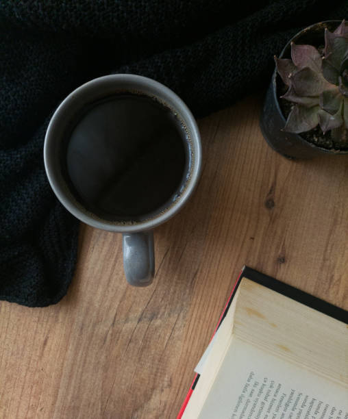 istock a cup of dark coffee with an old book and a plant 2150053313