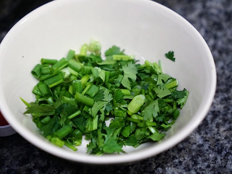 a photography of a bowl of chopped green vegetables on a counter.