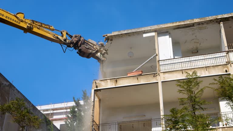 Excavator crane with strong claw pincer attachment crushes roof of demolished building