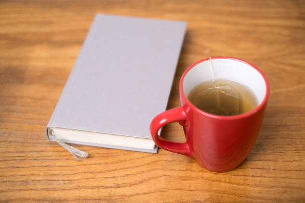 A cozy atmosphere with a steaming cup next to a book, which invites you to relax and read.