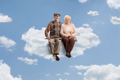 Elderly couple sitting on a cloud up in the sky