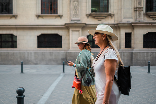 Two female tourists walk down an old street.