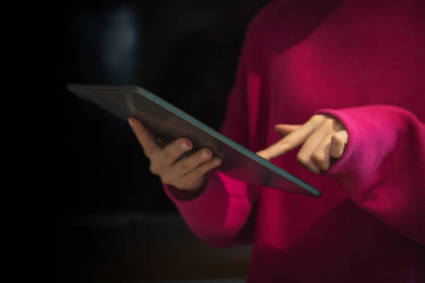 istock Young girl uses a digital tablet on a dark background 2150061785