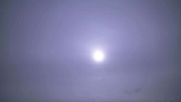 Full moon shining over violet blue skyline with fog, motion lapse sky at night