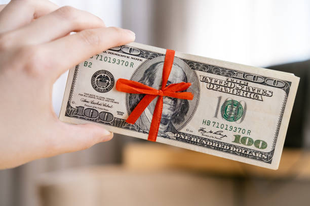 istock Bundle of dollars is wrapped in a thin red ribbon folded into a bow 2150064827