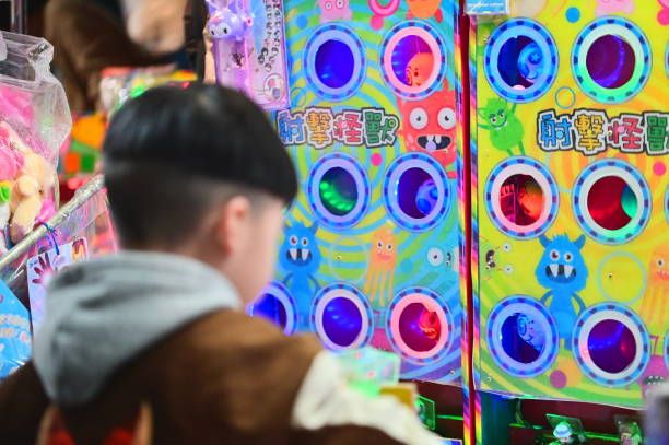 Taiwan - Feb 28, 2024:At a children's arcade stall in Ningxia Night Market in Taipei, a close-up of a child operating a monster shooting game machine, the lights on the machine are bright and colorful