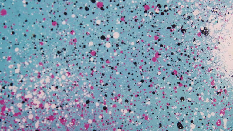 Speckled black white and pink frosted glass is coated with spray paint in urban setting
