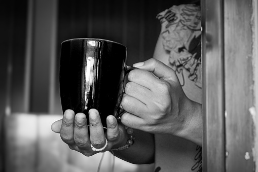 Hand holding a mug containing a drink welcoming the morning