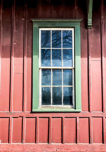 Two wooden windows with operational shutters mounted on the side of a rustic barn-style building