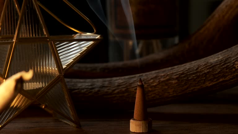 Slow orbit shot of a incense cone burning with smoke in a dark esoteric setting, in slow motion