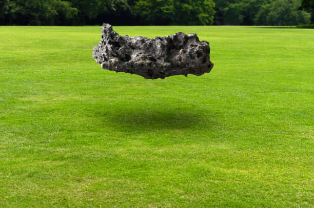 Meteorite floating in mid-air over the green grass with shadow.