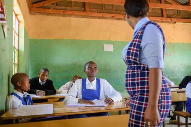 istock Female student in school classroom looking up at teacher 2150078043