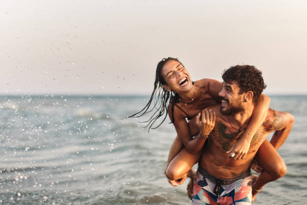 Cheerful couple having fun while piggybacking at sea.