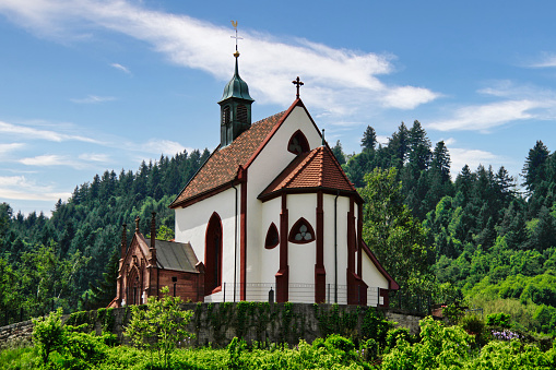 A beautiful medieval German church nestled atop a mountain, surrounded by lush green forest in the summer.