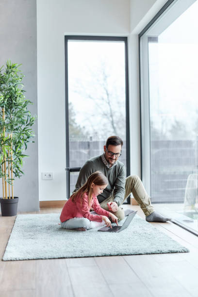 istock Smiling single father and his daughter using computer at home. 2150078850