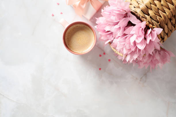 istock Wicker basket with pink flowers, morning coffee cup, gift box on stone table, top view. Flat lay composition for Mother's Day, International Women's Day, Birthday. 2150079356