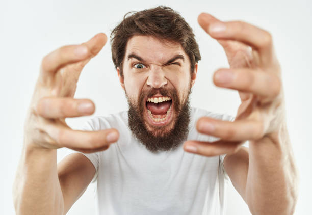 istock A bearded man in a white T-shirt gestures with his hands on a light background 2150081321
