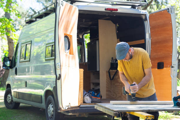 istock Man sanding wood with an electric sander customizing a camper van 2150083335
