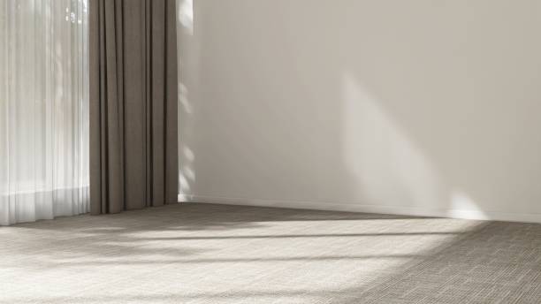 istock Cream wall room in sunlight from window with sheer and beige blackout curtain, tree shadow on white baseboard, carpet floor 2150083480