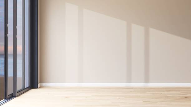 istock Empty room with large blank beige brown wall, wood laminate parquet floor in evening sunlight from glass sliding door 2150083564
