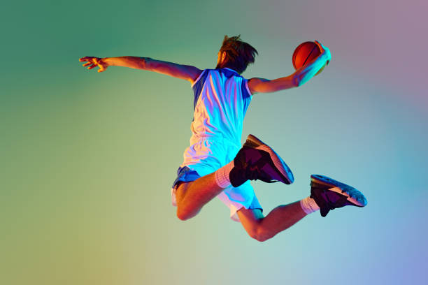 istock Competitive man, athlete in motion, training, playing basketball against gradient background in neon light 2150085384
