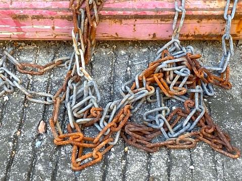 Dirty and old iron chain with rusty in three colors, gray, orange and brown on the concrete floor