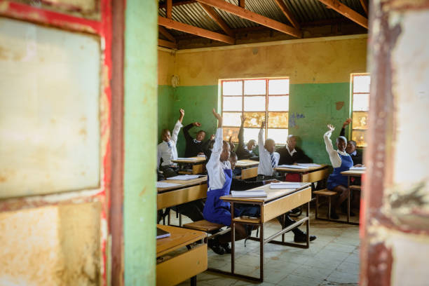 istock Outside window view into African Secondary education in rural setting hands raised 2150086011