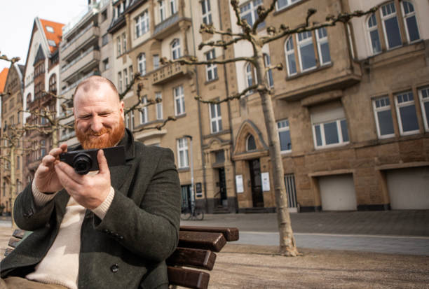 istock Handsome redhead tourist man interacting with a digital camera 2150086037