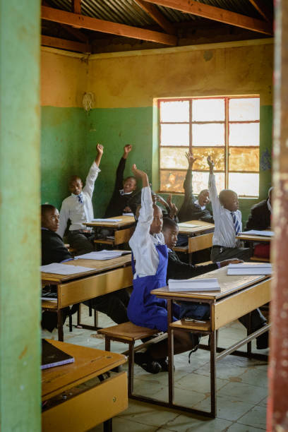 istock Outside view into African Secondary education in rural setting hand raised 2150086043