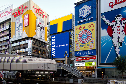 Osaka, Japan - November 8, 2023: Tourists visit Dotonbori District of Osaka city, which is the famous tourist area full of billboard advertising along the Dotonbori canal and Dotonboribashi bridge.
