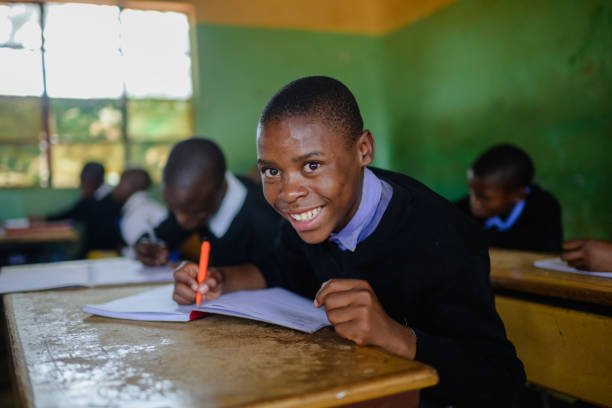 istock Schoolboy in uniform sitting in classroom looking at camera smiling 2150086411