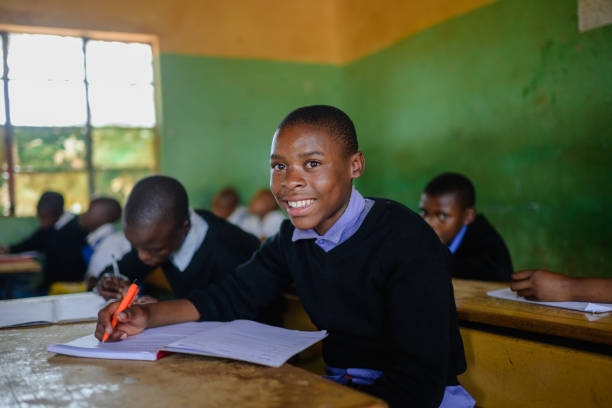 istock Schoolboy in uniform sitting in classroom looking at camera with a smile 2150086444