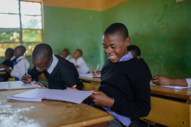 istock Schoolboy in uniform sitting in classroom looking at his work feeling proud smiling 2150086462