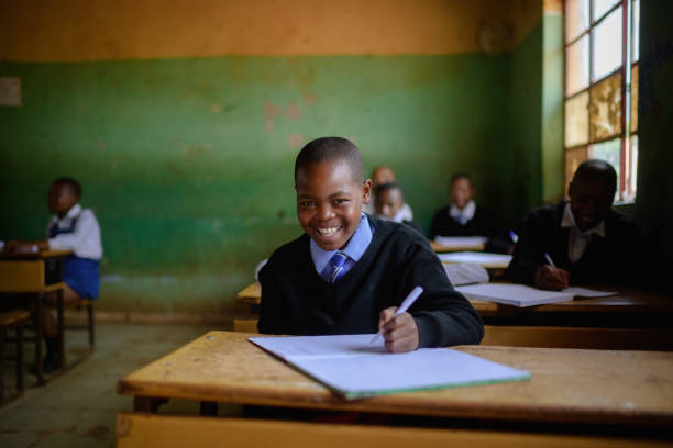 istock Cute Schoolboy in uniform sitting in classroom looking at camera smiling 2150086616